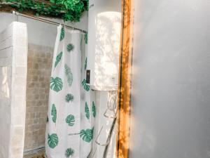 a bathroom with a shower curtain with leaves on it at Simple Wooden house in Moçarria