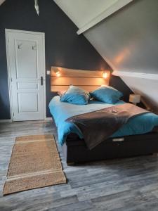 a bedroom with a large bed with blue pillows at la longère charmante in Céaux