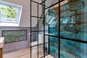 a glass wall in a bathroom with a fish tank at Finest Retreats - Blue Seas in Mousehole
