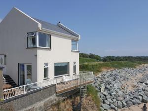 a white house with a balcony and a rocky beach at Beach House in Duncannon