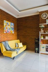a yellow couch in a room with a brick wall at Amarillo Lembang in Lembang