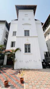a white building with plants in front of it at Pepper Route, Fort Kochi in Fort Kochi