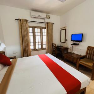 a bedroom with a bed and a desk and a television at Pepper Route, Fort Kochi in Fort Kochi