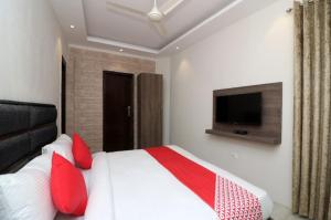 a bedroom with a bed with red pillows and a tv at Hotel Kanha Classic, Kanpur in Kānpur