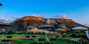 une montagne avec des chaises et des parasols devant elle dans l'établissement Hotel Eros, à Vulcano