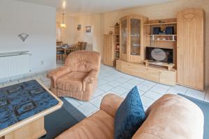 sala de estar con sofá, sillas y TV en Ferienhaus Seeschwalbe en Norddeich