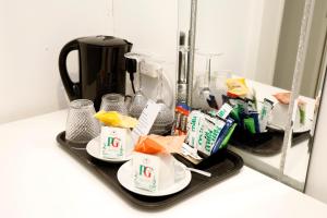 a tray with cups and food on it in front of a mirror at Bexley Village Hotel in Bexley