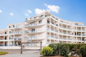 埃爾基的住宿－Appartement a moins de 100m de la plage du Bourg pour 4 personnes，带阳台和树木的白色公寓大楼