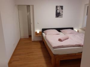 una camera da letto con un letto con lenzuola bianche e cuscini rosa di Ferienwohnung am alten Bahndamm a Frielendorf