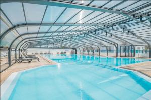 a large indoor swimming pool with a glass ceiling at Joli Chalet a Bretignolles sur mer pour 6 personnes in Brétignolles-sur-Mer