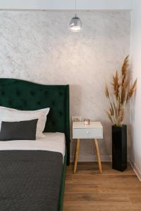 um quarto com uma cama com uma cabeceira verde e uma mesa lateral em SummerTime Tomis Villa Studio Mamaia Nord em Năvodari