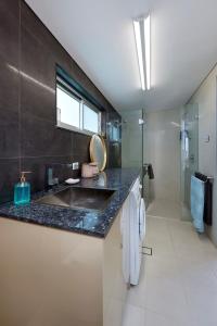 La salle de bains est pourvue d'un lavabo et d'un comptoir. dans l'établissement Sandon Point Coastal Abode, à Bulli