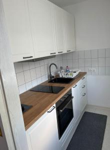 MH Apartment في كونيغسبرون: مطبخ مع دواليب بيضاء ومغسلة