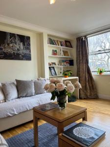 een woonkamer met een bank en een tafel met bloemen bij Hyde Park,3 min walk,Family home! 2 Bedrooms & 2 Bathrooms Apartment! Fantastic Location in Londen
