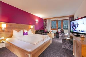 a hotel room with a large bed and a flat screen tv at Hotel Gabriela INKLUSIVE SUPER SOMMER CARD in Serfaus