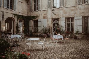 een man aan een tafel voor een gebouw bij La Fontaine Racine - Chambres d'hôtes in La Ferté-Milon