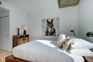 Un dormitorio con una cama blanca con una foto de un caballo en Les Immeubles Charlevoix - Le 760705 en Quebec
