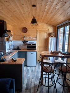 een keuken met een houten plafond en een tafel en stoelen bij Roulotte au paradis in Le Repaire