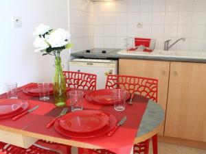 ラ・ロシェルにあるAppartement La Rochelle, 2 pièces, 4 personnes - FR-1-246-17の白花の花瓶と赤皿のテーブル