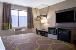ein Hotelzimmer mit einem Bett und einem Flachbild-TV in der Unterkunft Super 8 by Wyndham Merrillville in Merrillville