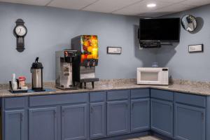 a kitchen with blue cabinets and a counter with a microwave at Super 8 by Wyndham Merrillville in Merrillville