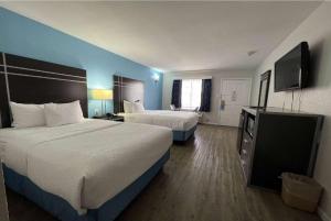 a hotel room with two beds and a flat screen tv at Days Inn by Wyndham Orange in Orange