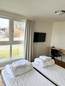 a bedroom with two beds and a desk and a television at Vandrarhem Nattmössan in Kungsbacka