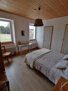1 dormitorio con cama, mesa y ventana en Maison La Vigne - Gîtes et Chambres d'hôtes, en Le Chambon-sur-Lignon