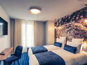 a hotel room with two beds and a table at Hôtel Mercure Paris Suresnes Longchamp in Suresnes