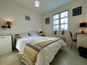 sypialnia z łóżkiem i biurkiem oraz dwoma oknami w obiekcie Maison 5 pièces près de la plage, jardin clos, 8 couchages – Saint-Georges-d’Oléron - FR-1-246A-175 w mieście Saint-Georges-dʼOléron