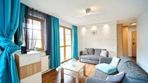 カルパチにあるApartamenty Every Sky Karpacz Prusa 2b/9の青いカーテンとソファのあるリビングルーム