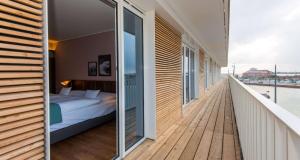 1 dormitorio con 1 cama en un balcón de madera en THE LIBERTY Hotel Bremerhaven BW Signature Collection, en Bremerhaven