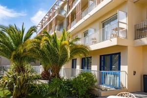 un edificio con palmeras delante en Best Western Arcachon Le Port en Arcachón