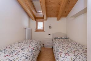 1 Schlafzimmer mit 2 Betten und Holzdecke in der Unterkunft Casa Milena in Pozza di Fassa