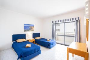um quarto com 2 camas azuis e uma varanda em Sunholidays Apartment by Umbral em Albufeira