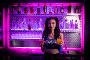 a woman standing in a bar holding a drink at Splash Bar and Guesthouse in Pattaya