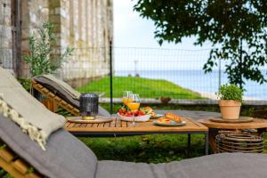 una mesa de madera con comida y vasos de zumo de naranja en Exclusive Seafront Bacchus Apartment, en Poreč