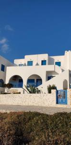 un gran edificio blanco con puertas y ventanas azules en Glaros Rooms, en Koufonisia