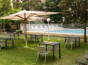 a group of tables and chairs with an umbrella next to a pool at Appart Hotel Corte HR in Corte