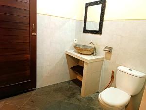 ein Badezimmer mit einem Waschbecken, einem WC und einem Spiegel in der Unterkunft Sanga Suites in Ubud