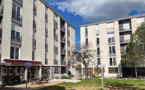 two large white buildings with a picnic table in a courtyard at Appart Hotel HR in Corte