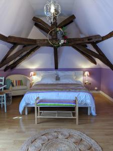 - une chambre avec un grand lit aux murs violets et un lustre dans l'établissement La Borie du Chevrier, à Sainte-Croix-de-Beaumont