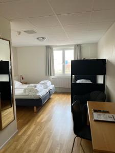 a room with two beds and a table and a desk at Vandrarhem Nattmössan in Kungsbacka