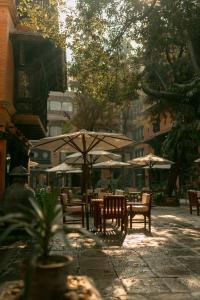 a patio with tables and chairs and an umbrella at The Dwarika's Hotel in Kathmandu