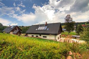 a house with solar panels on top of a field at Wellness Chata Kastanek in Kvilda