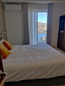 a bedroom with a large white bed with a window at SouthShore Accommodation in Marsaskala