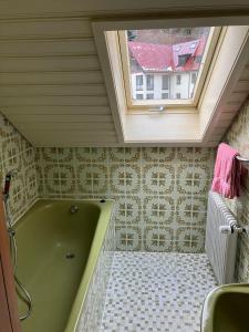 ein Bad mit einer grünen Badewanne und einem Fenster in der Unterkunft Gästehaus Lickert Familie Dreher in Hinterzarten