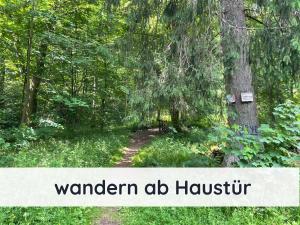un sentier dans les bois avec les mots wanden al hogtu dans l'établissement Der Fuchsbau - 3 separate Blockhäuser - ruhige Lage - 50m bis zum Wald - eingezäunter Garten, à Bad Sachsa