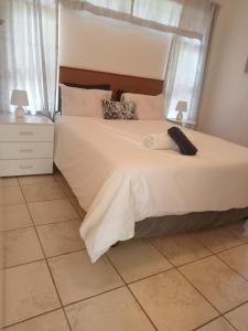 1 dormitorio con 1 cama blanca grande y suelo de baldosa en 27@caravenseria, en Hibberdene