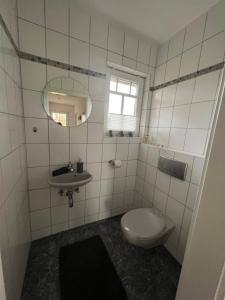een badkamer met een toilet, een wastafel en een spiegel bij Weideblick in Upgant-Schott